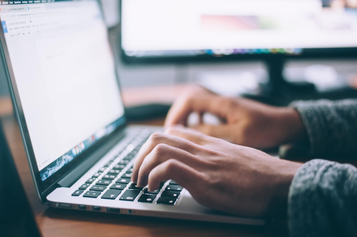 Photo of two hands typing on a laptop